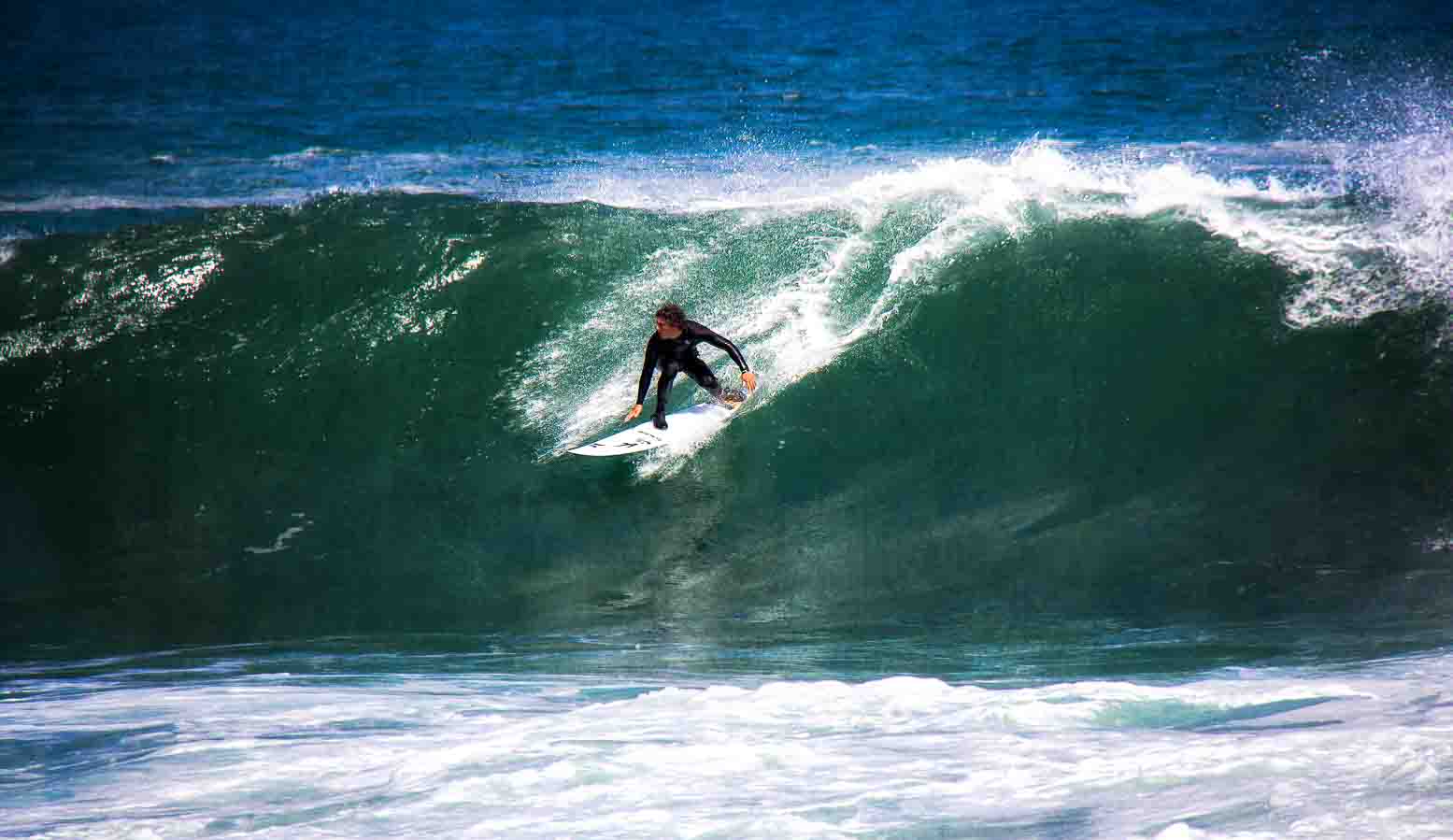 Surfer carving down the face of a deep green wave