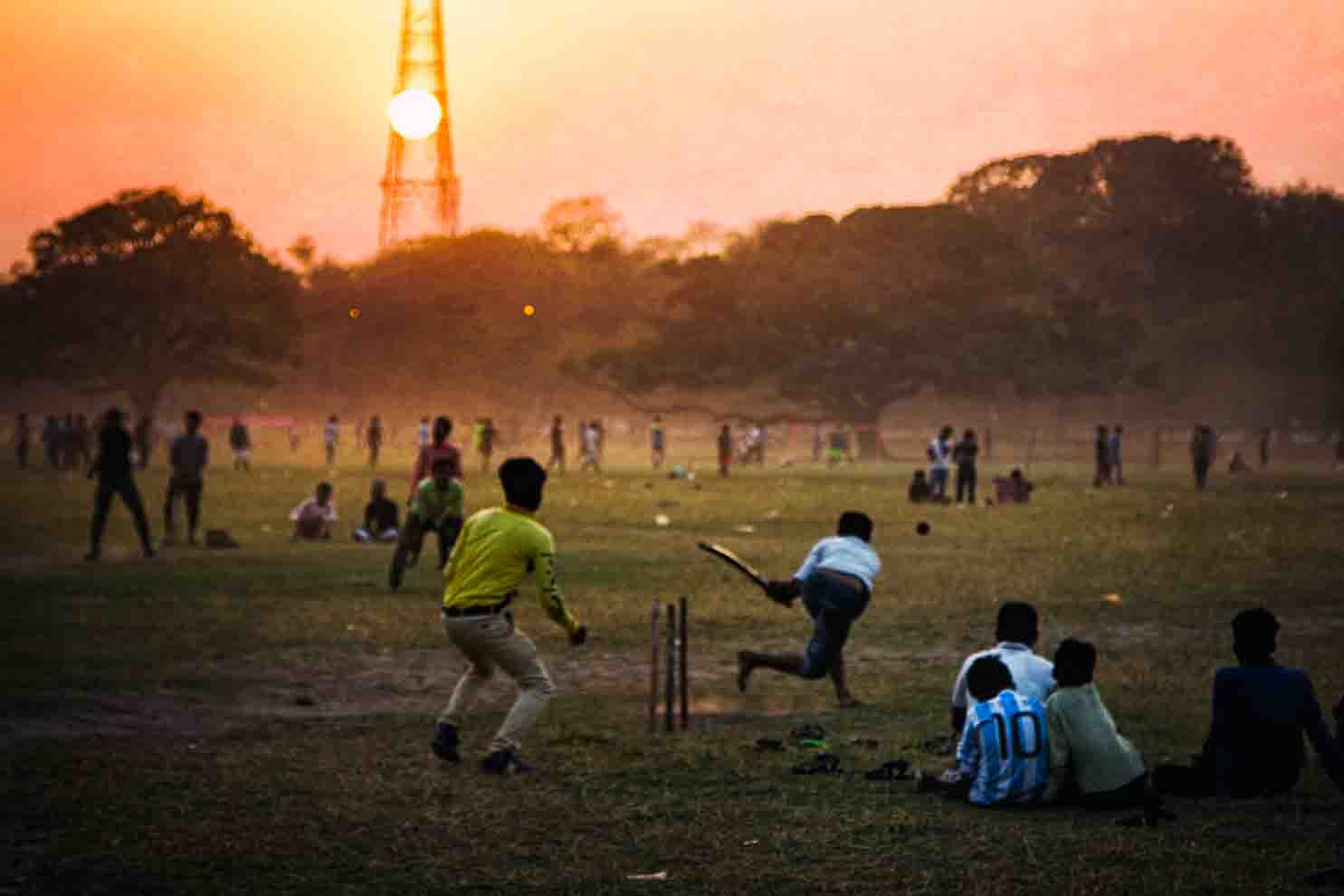 Children playing cricket on the Maidan at sunset