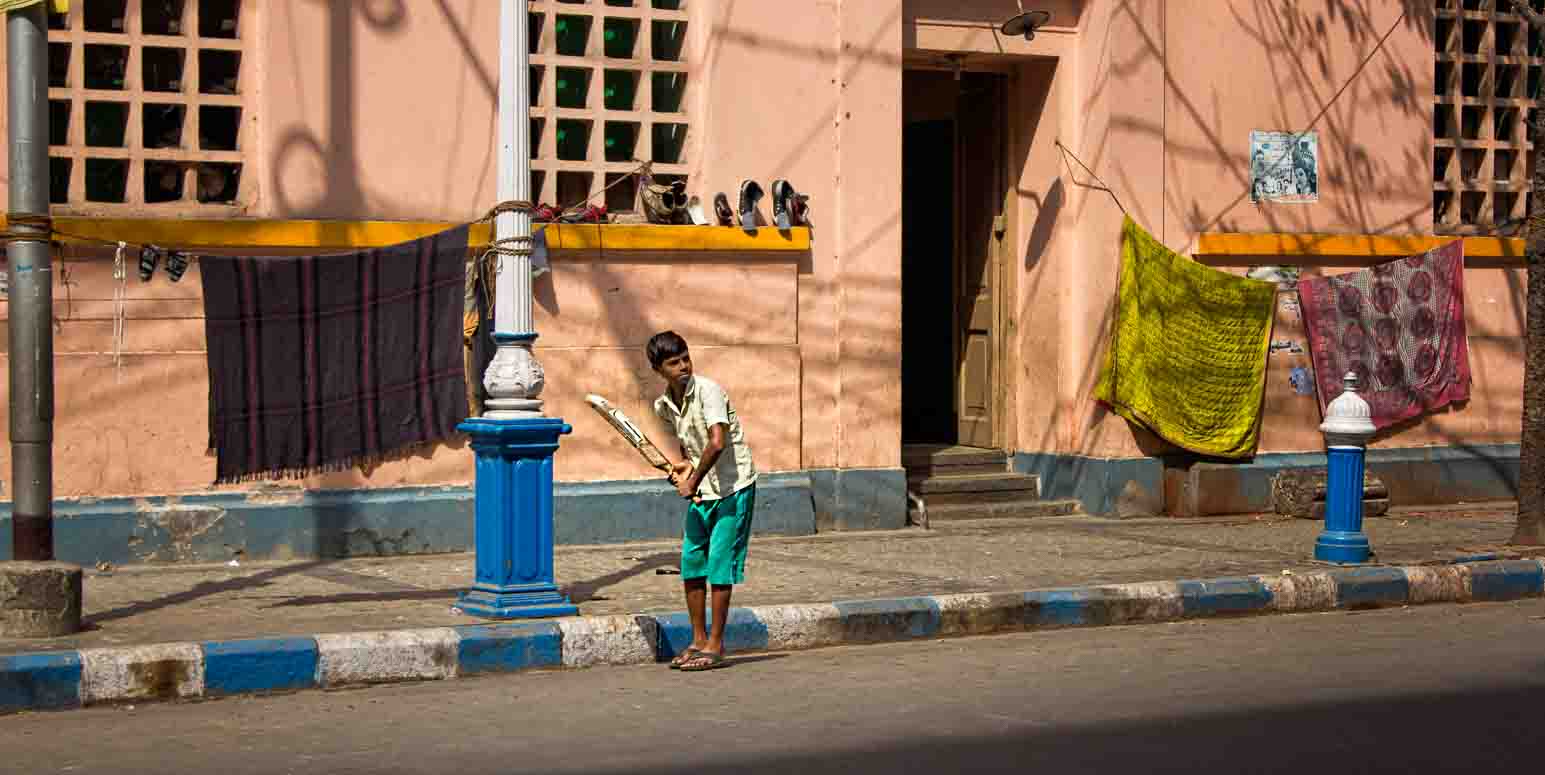 Boy with a cricket bat alone on a quiet residential street