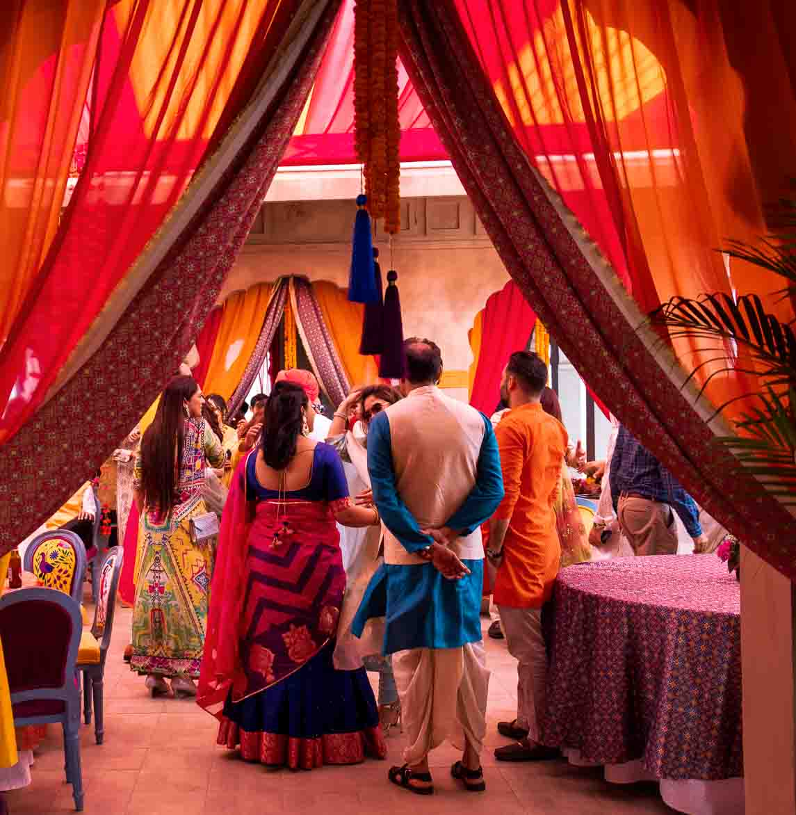 Wedding ceremony beneath saffron and red drapery, family gathered