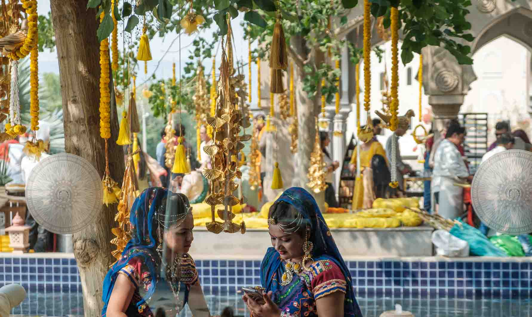 Two women in bridal dress framed by hanging golden bell garlands