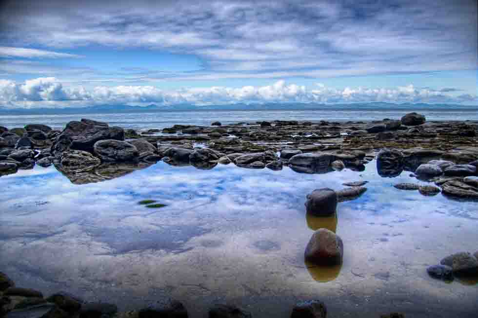Tidal pools below a cloud-streaked sky