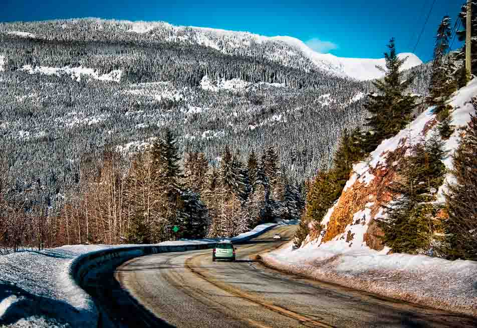 A car on a snow-lined mountain highway