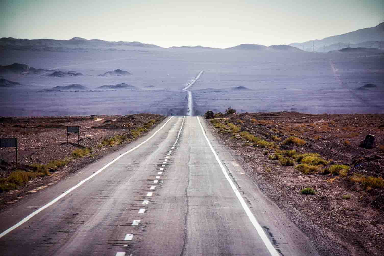 Empty highway running straight into a hazy desert horizon